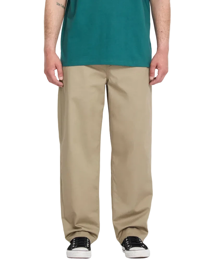 Person wearing a green shirt and beige pants fit