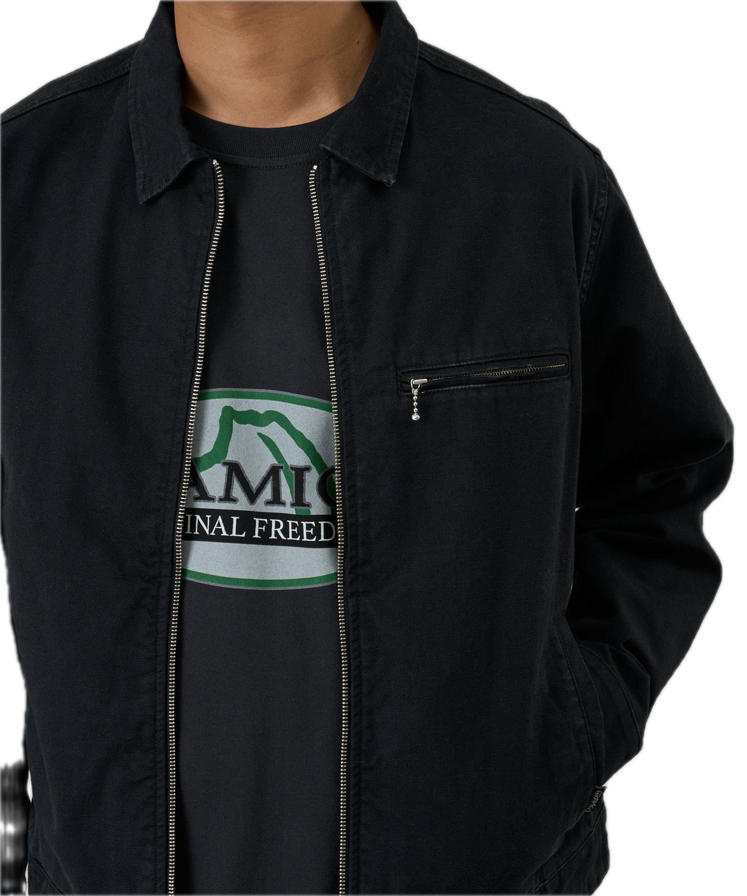 Person wearing a black jacket over a graphic t-shirt with text and logo.