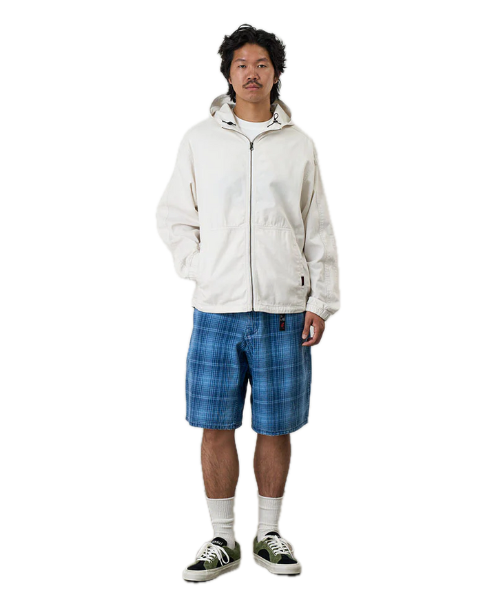 Person wearing a white jacket and blue plaid shorts 