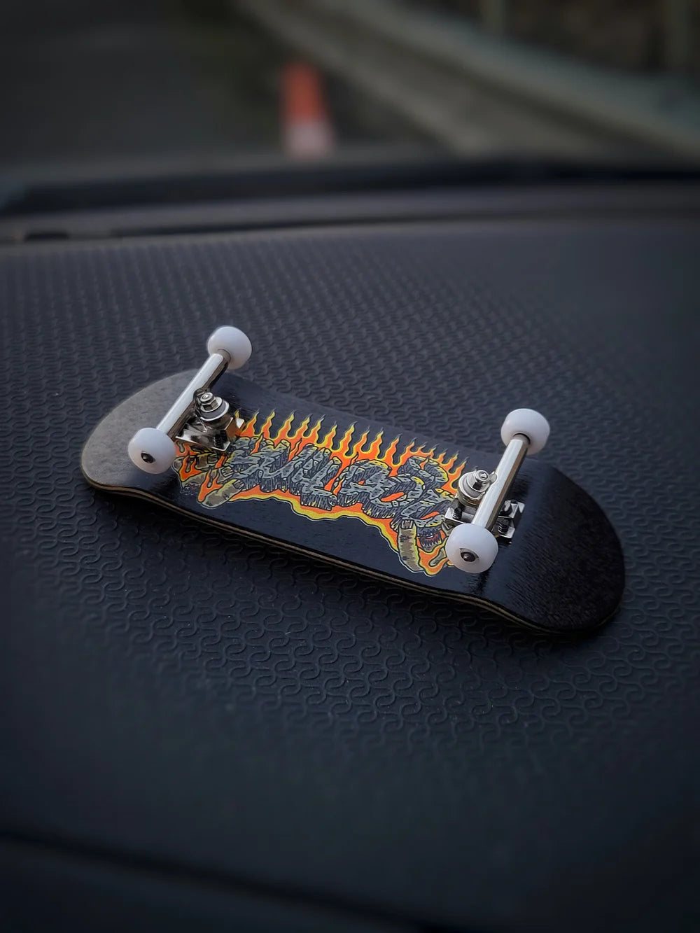 Small skateboard with colorful design on a textured black surface