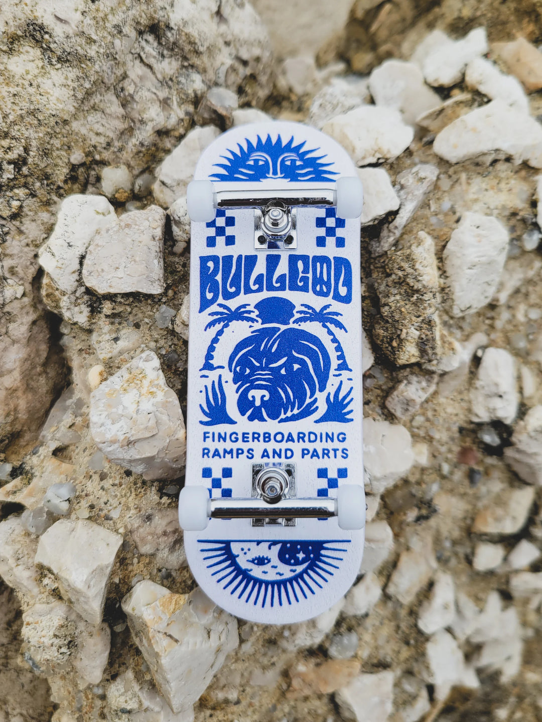 Fingerboard with blue and white design on a rocky surface