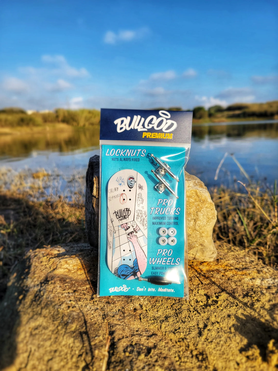 Bulldoog skateboard parts box on a rock with a lake and sky background