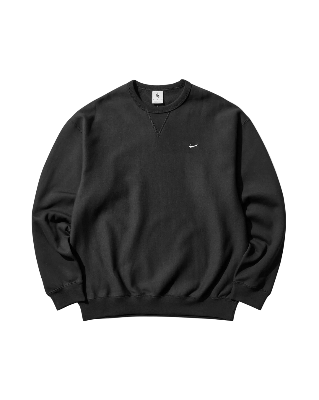 A black crewneck sweatshirt with a small white Nike Swoosh logo on the left chest, displayed flat against a light gray background.