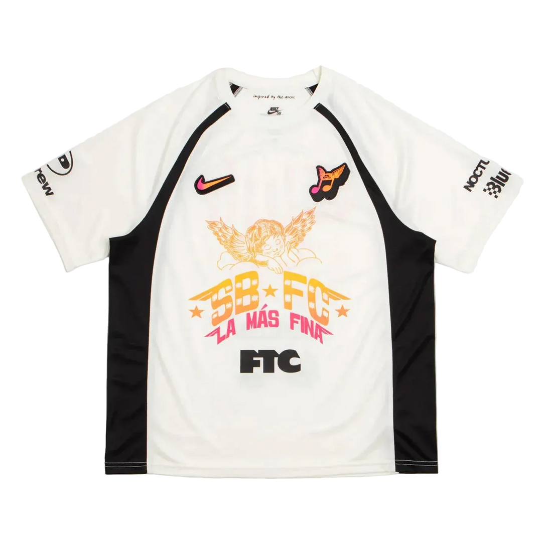 A white and black short-sleeve soccer jersey with a large orange, pink, and black graphic on the front reading 'SB FC LA MAS FINA' and 'FTC'. The jersey features a Nike swoosh on the right chest, a soccer ball with a bird on the left chest, and sponsor logos on the sleeves.