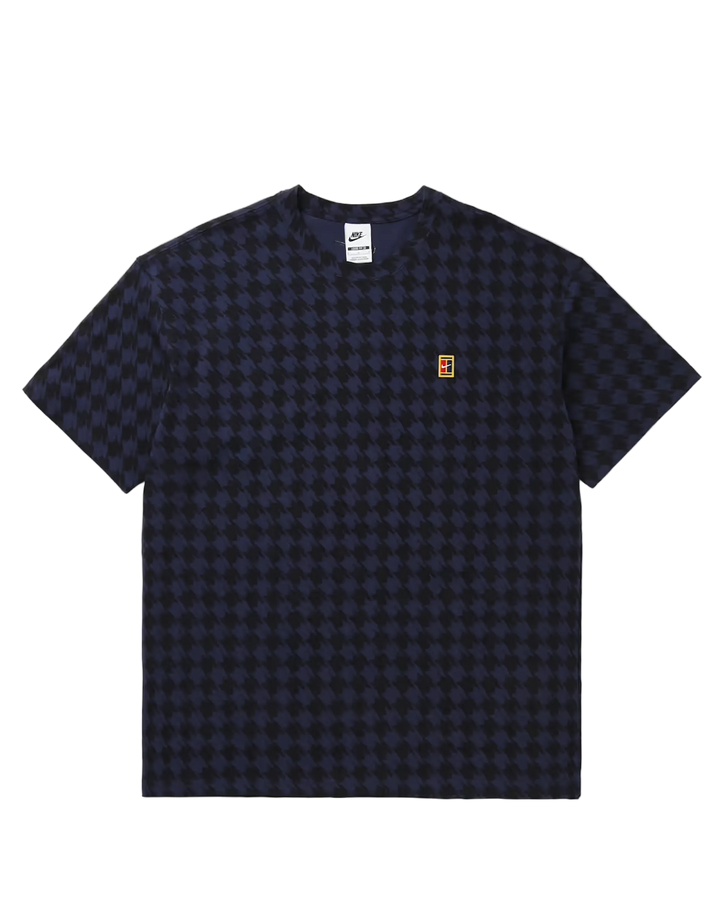 A dark navy blue short-sleeve t-shirt with a subtle tonal checkerboard pattern, featuring a small orange and white logo on the left chest, displayed flat against a light gray background.